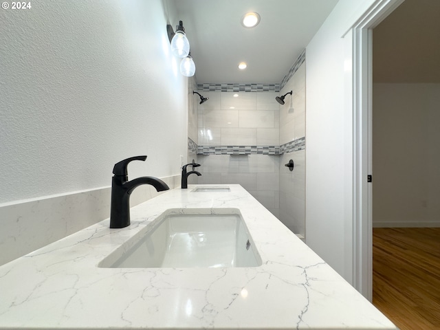 bathroom featuring vanity, tiled shower, and wood-type flooring