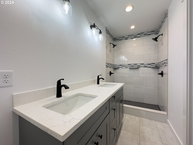 bathroom with tile patterned flooring, a tile shower, and vanity