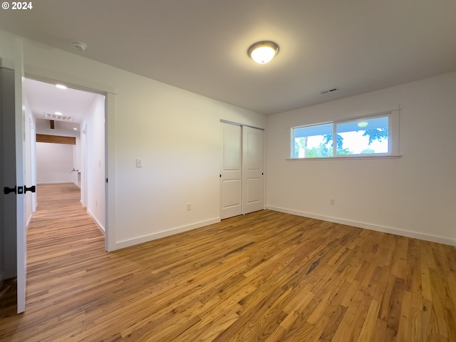 unfurnished bedroom with light wood-type flooring and a closet