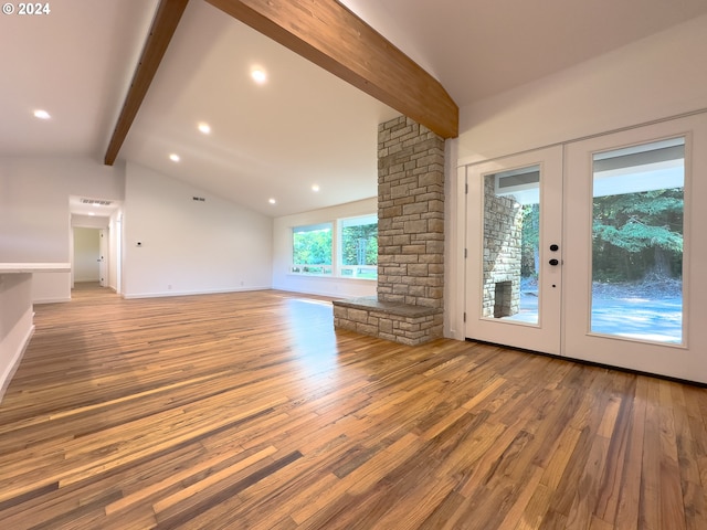 unfurnished living room with lofted ceiling with beams, hardwood / wood-style flooring, and french doors