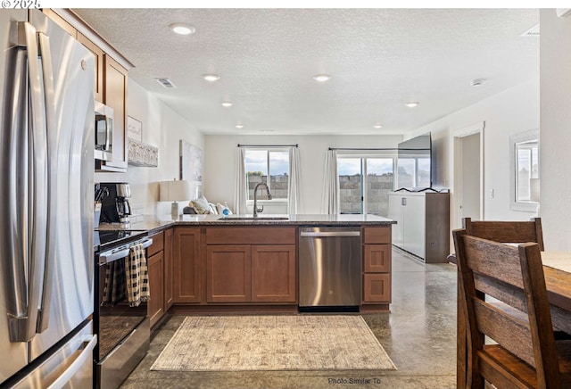 967 NE 11th St, Hermiston, OR 97838 - kitchen with stainless steel appliances, a sink, a peninsula, a textured ceiling, and finished concrete floors