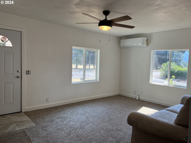 carpeted foyer entrance featuring ceiling fan, a healthy amount of sunlight, a textured ceiling, and a wall unit AC