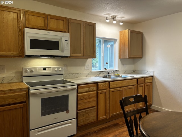 kitchen with dark hardwood / wood-style flooring, sink, a textured ceiling, and white appliances