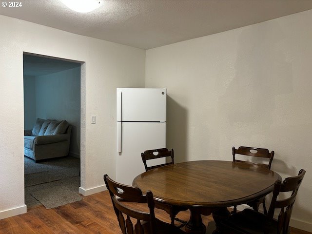 dining space with a textured ceiling and dark hardwood / wood-style flooring