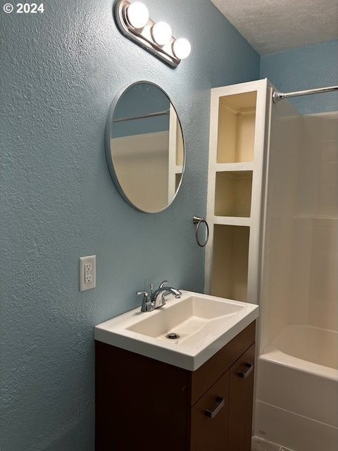 bathroom featuring vanity,  shower combination, and a textured ceiling