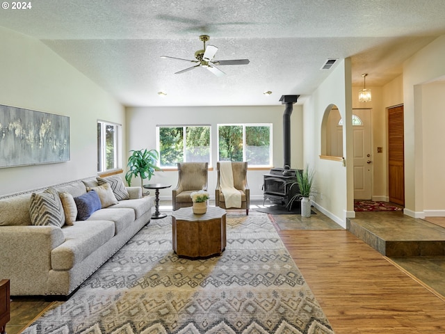 living room with hardwood / wood-style floors, lofted ceiling, a wood stove, and a textured ceiling