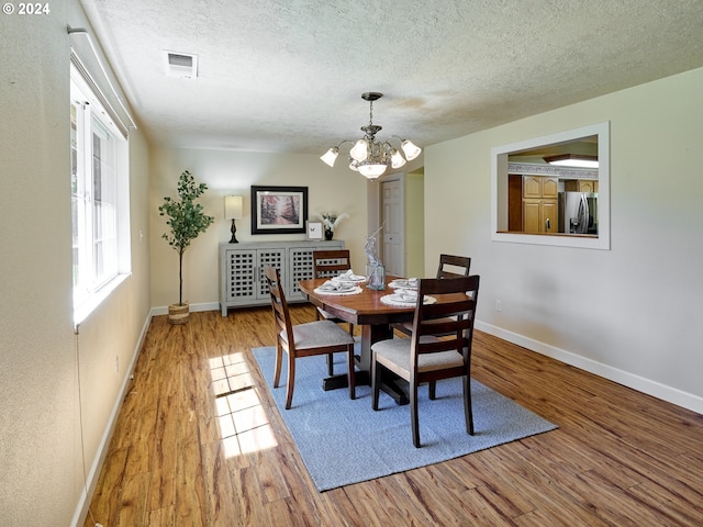 dining room featuring hardwood / wood-style floors, a textured ceiling, and an inviting chandelier