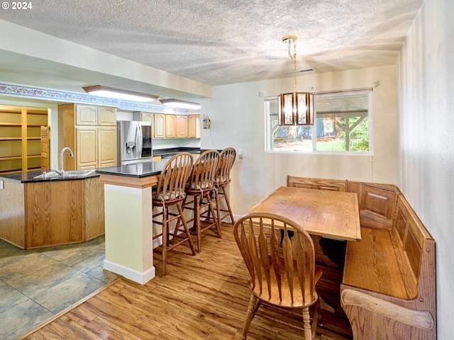 dining space featuring sink, an inviting chandelier, a textured ceiling, and light hardwood / wood-style flooring