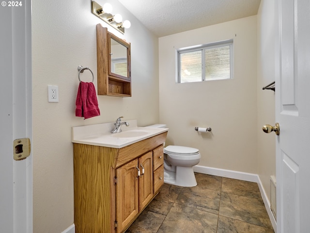 bathroom featuring vanity, a textured ceiling, and toilet