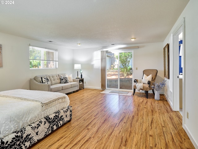 bedroom with a textured ceiling, light hardwood / wood-style flooring, and access to outside