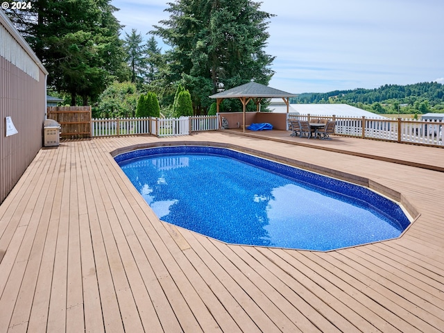 view of pool with a deck with water view and a gazebo