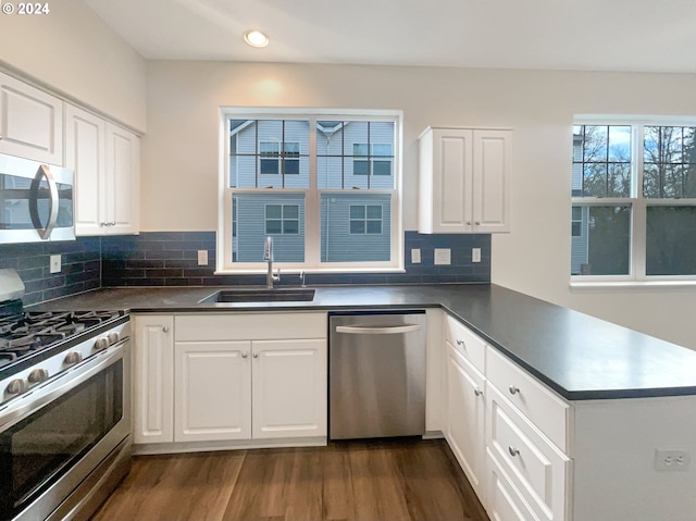 kitchen featuring sink, dark hardwood / wood-style flooring, white cabinets, appliances with stainless steel finishes, and backsplash