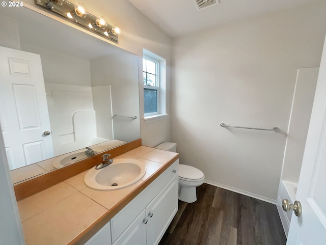 full bathroom with bathtub / shower combination, toilet, hardwood / wood-style flooring, and vanity with extensive cabinet space