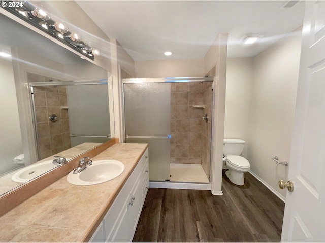 bathroom featuring vanity with extensive cabinet space, toilet, a shower with door, and hardwood / wood-style floors