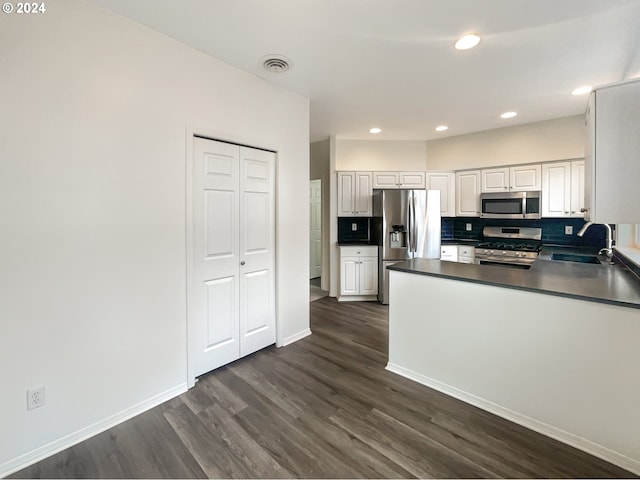 kitchen featuring appliances with stainless steel finishes, dark wood-type flooring, backsplash, sink, and white cabinetry