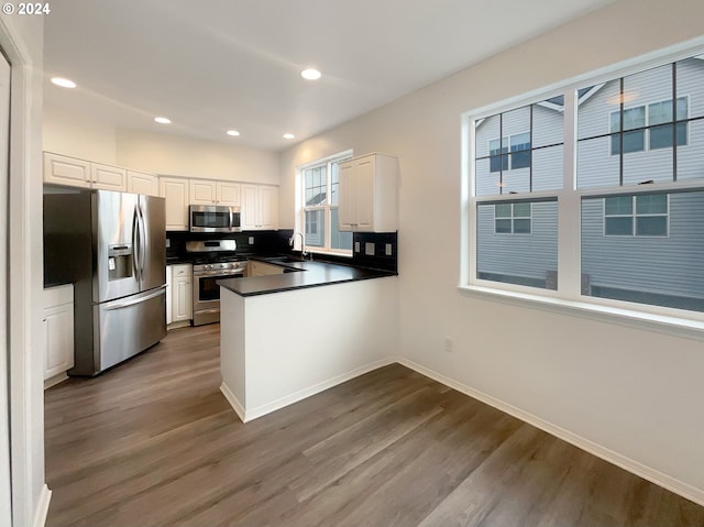 kitchen with stainless steel appliances, tasteful backsplash, white cabinetry, dark hardwood / wood-style flooring, and sink