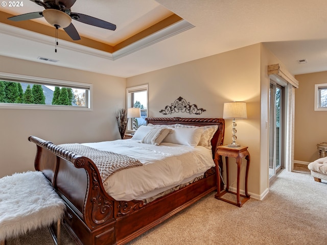 carpeted bedroom with ceiling fan and a tray ceiling