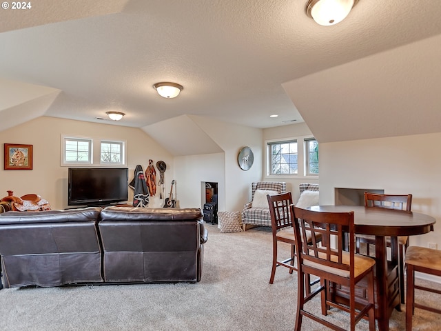 carpeted living room with a textured ceiling and vaulted ceiling