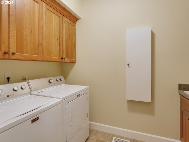 laundry room featuring cabinets, light tile patterned floors, and independent washer and dryer