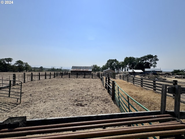 view of yard with an enclosed area, a rural view, and an outdoor structure