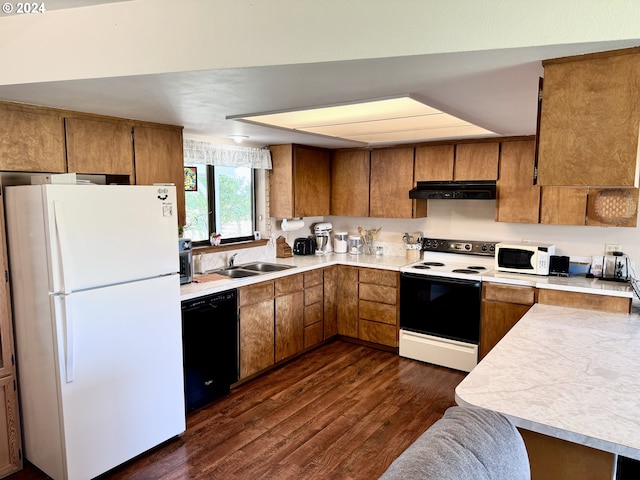 kitchen featuring white appliances, brown cabinets, a sink, and under cabinet range hood