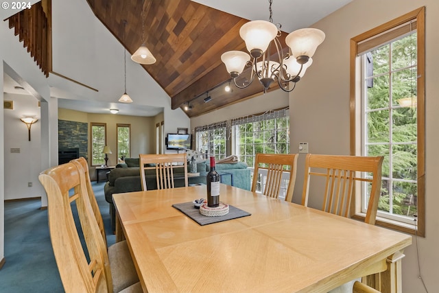 dining space with carpet flooring, a fireplace, plenty of natural light, and an inviting chandelier