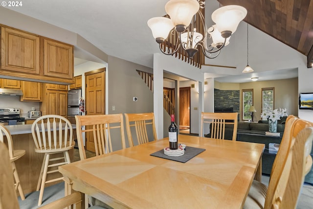 dining room with a fireplace, a chandelier, and lofted ceiling