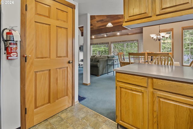 kitchen featuring light colored carpet, hanging light fixtures, lofted ceiling, and a notable chandelier