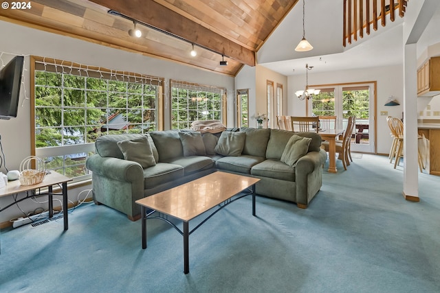 carpeted living room featuring a healthy amount of sunlight, rail lighting, high vaulted ceiling, and an inviting chandelier