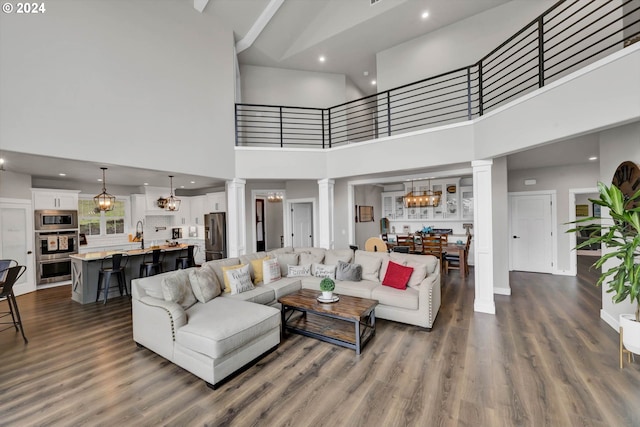 living room with a high ceiling, sink, ornate columns, and dark hardwood / wood-style floors