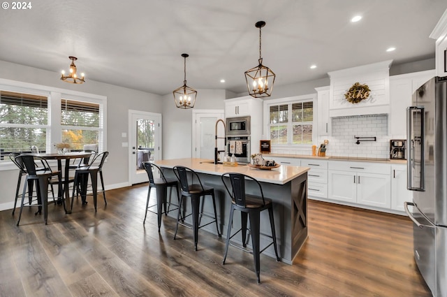 kitchen featuring white cabinetry, appliances with stainless steel finishes, pendant lighting, and an island with sink