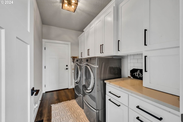 laundry room featuring a textured ceiling, dark hardwood / wood-style flooring, cabinets, and washing machine and clothes dryer