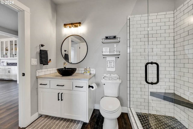 bathroom with hardwood / wood-style flooring, vanity, toilet, and walk in shower