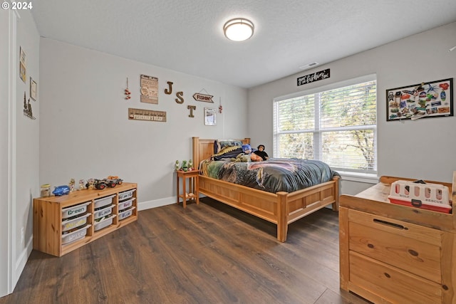 bedroom with dark hardwood / wood-style floors and a textured ceiling