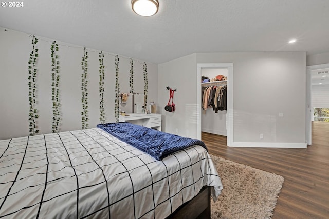 bedroom featuring hardwood / wood-style flooring, a textured ceiling, a closet, and a spacious closet