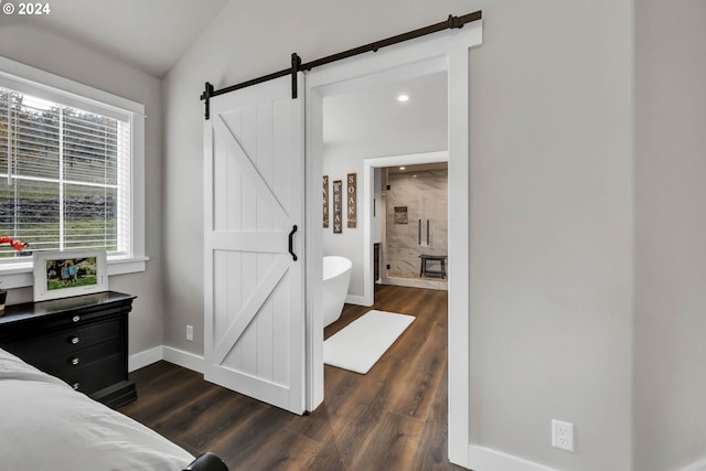 bedroom featuring ensuite bathroom, dark wood-type flooring, a barn door, and vaulted ceiling