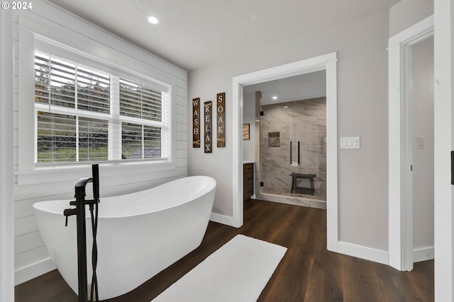 bathroom featuring a wood stove, hardwood / wood-style flooring, and plus walk in shower