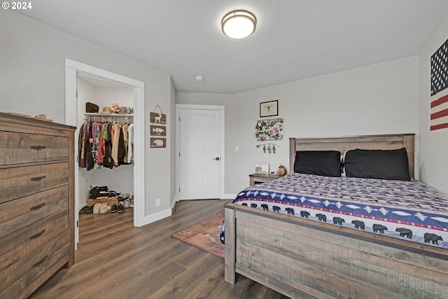 bedroom with a spacious closet, dark hardwood / wood-style floors, and a closet