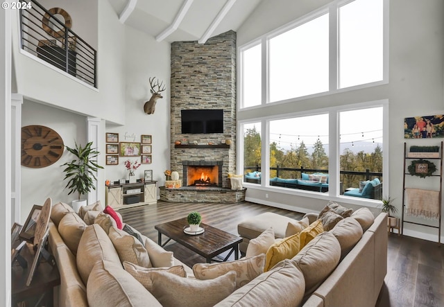 living room featuring beamed ceiling, dark hardwood / wood-style flooring, a stone fireplace, and high vaulted ceiling