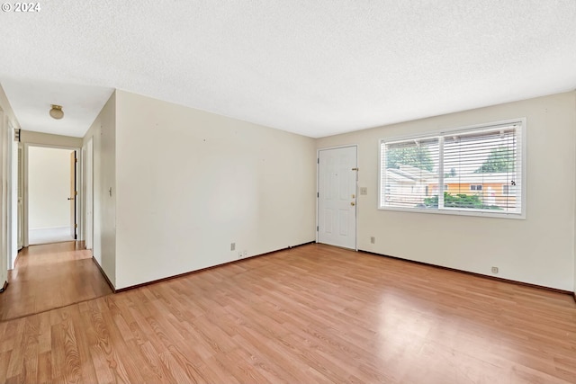 spare room featuring light hardwood / wood-style floors and a textured ceiling