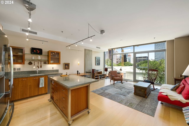 kitchen featuring stainless steel fridge, sink, a wall of windows, a center island, and light hardwood / wood-style floors