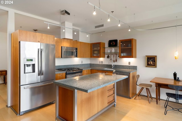 kitchen with a center island, sink, hanging light fixtures, light hardwood / wood-style flooring, and stainless steel appliances