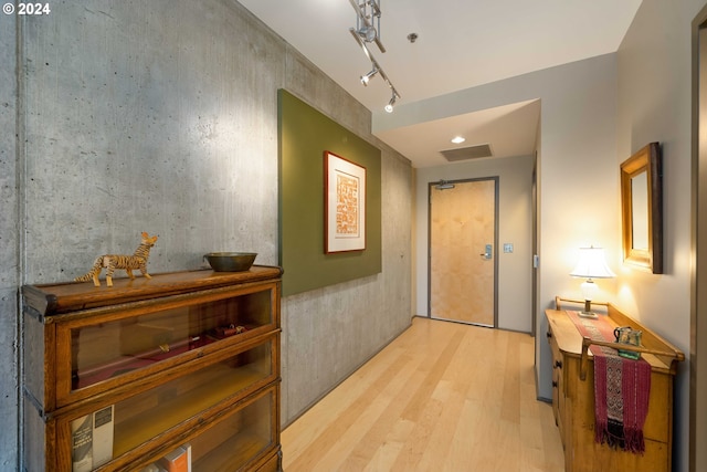 hall with rail lighting and light hardwood / wood-style flooring