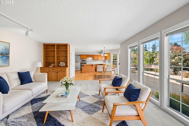 5393 SW Wichita St, Tualatin, OR 97062 - living room with light wood-type flooring, a textured ceiling, track lighting, and a chandelier