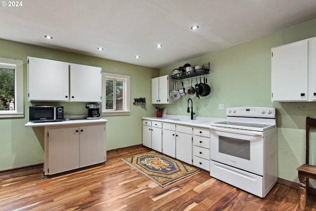 kitchen with white cabinets, light wood-type flooring, sink, and electric range