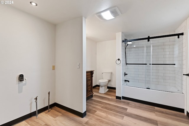 full bathroom featuring hardwood / wood-style floors, combined bath / shower with glass door, vanity, and toilet