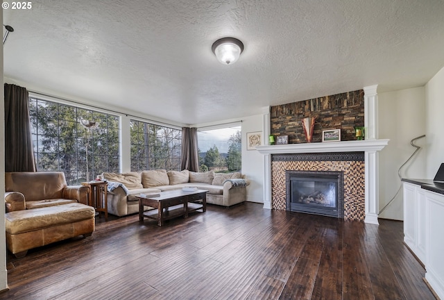 living room featuring a tile fireplace, dark wood finished floors, and a textured ceiling