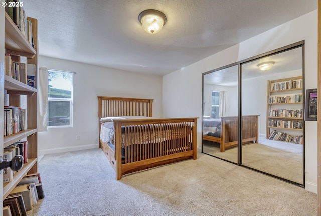 carpeted bedroom with a textured ceiling, a closet, and baseboards