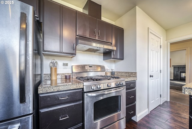 kitchen with tile counters, dark wood-style flooring, stainless steel appliances, dark brown cabinets, and under cabinet range hood