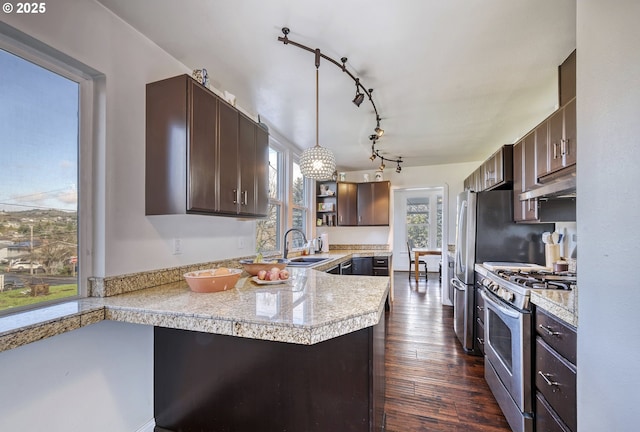 kitchen with dark wood-style floors, stainless steel gas stove, dark brown cabinetry, a peninsula, and under cabinet range hood